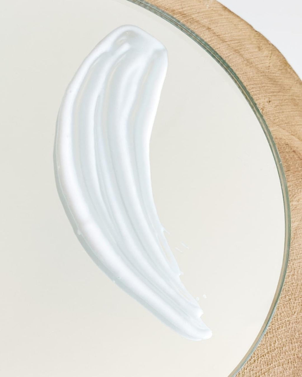 Glass plate with a wooden rim on a neutral background with a smear of Ultra Glow Going across it