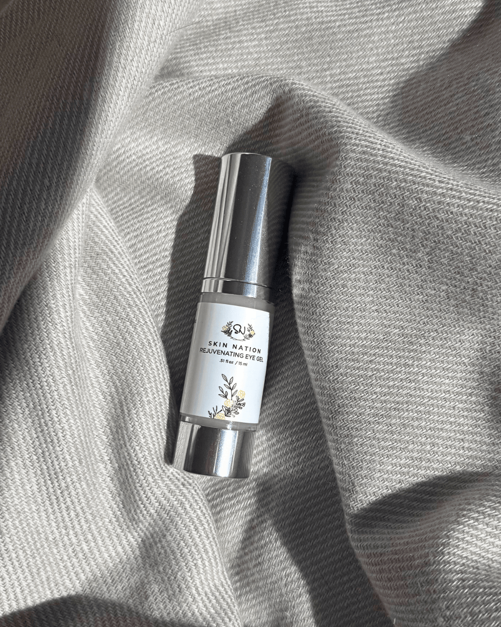 Skincare Rejuvenating Eye Gel bottle on a textured gray fabric background