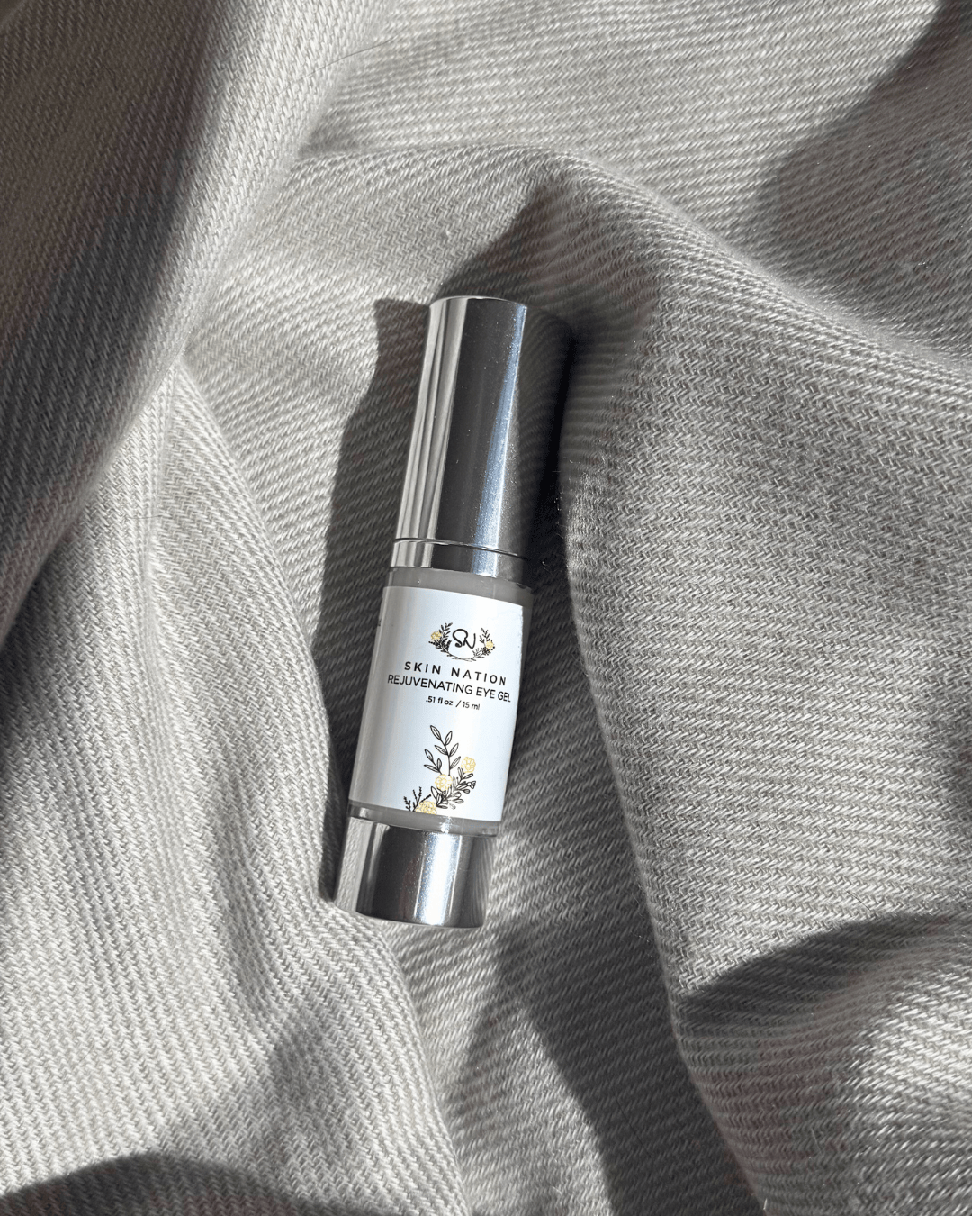 Skincare Rejuvenating Eye Gel bottle on a textured gray fabric background