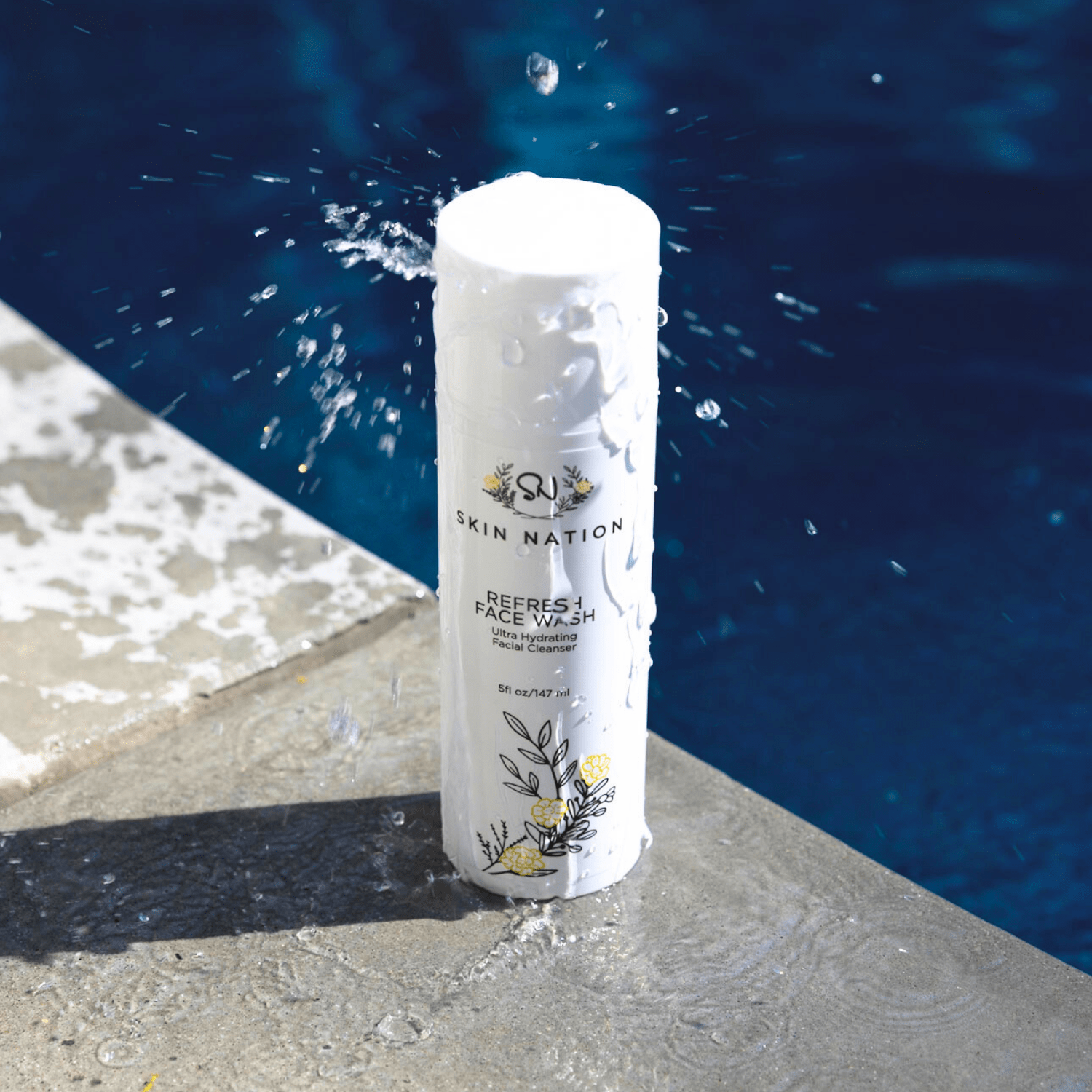 Skincare product labeled 'Skin Nation Face Wash' by a pool with water splashing around it.