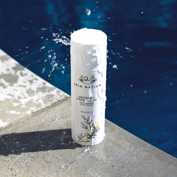 Skincare product labeled 'Skin Nation Face Wash' by a pool with water splashing around it.