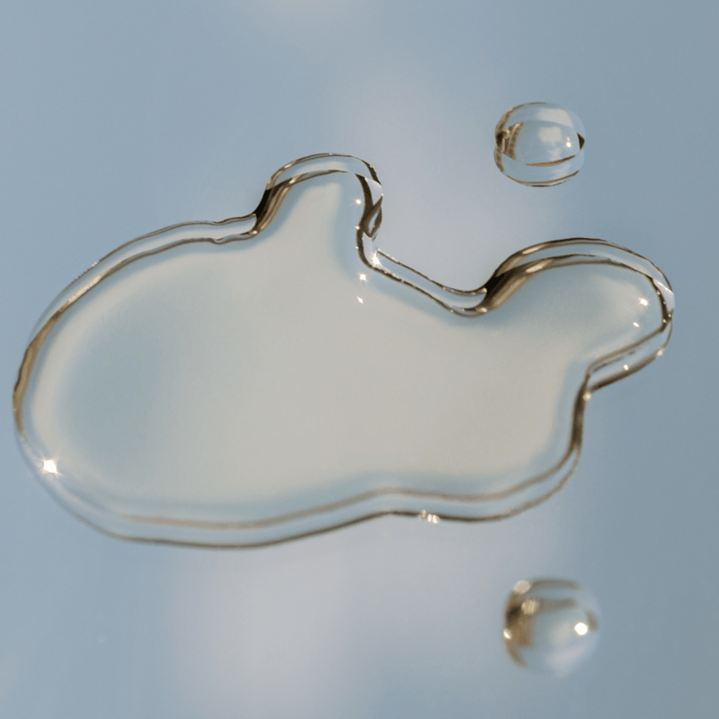 Clear liquid droplet of Toner on a reflective surface with a blue gradient background